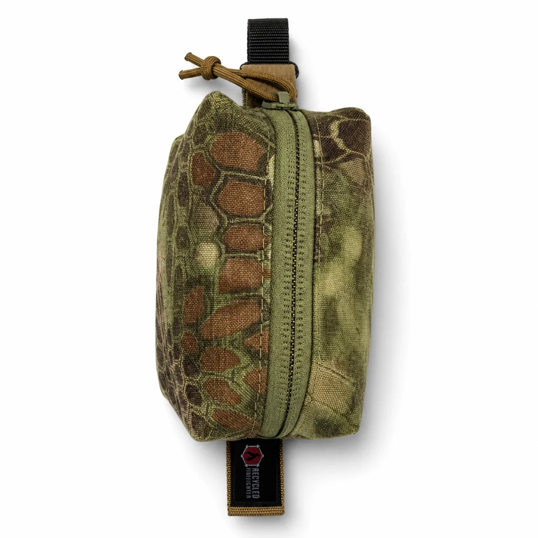 The Mandrake-pattern Hot Shot Commander Keychain Pouch from Recycled Firefighter showcases a dense woodland camo exterior on a compact, USA-built EDC clip organizer. It zips shut and clips securely to any belt loop, key ring, or pack strap for hands-free carry.
