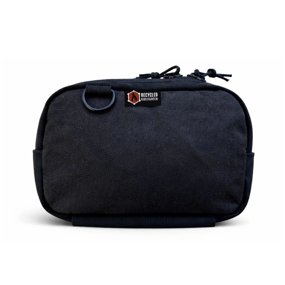 Recycled Firefighter Trailhound pack in all-black MSA bunker gear. The fabric has a distinct ripstop grid texture and a matte finish, paired with black hardware for a sleek, monochromatic tactical appearance.