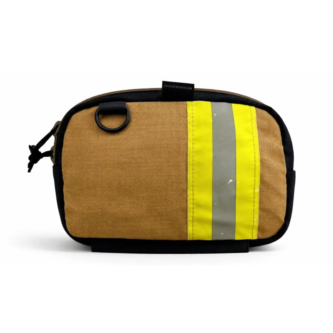 A brown bunker gear fanny pack by Recycled Firefighter featuring a wide, horizontal yellow and silver reflective safety stripe across the front. The pack is made from authentic repurposed firefighter turnout gear with black zippers and a side grommet.
