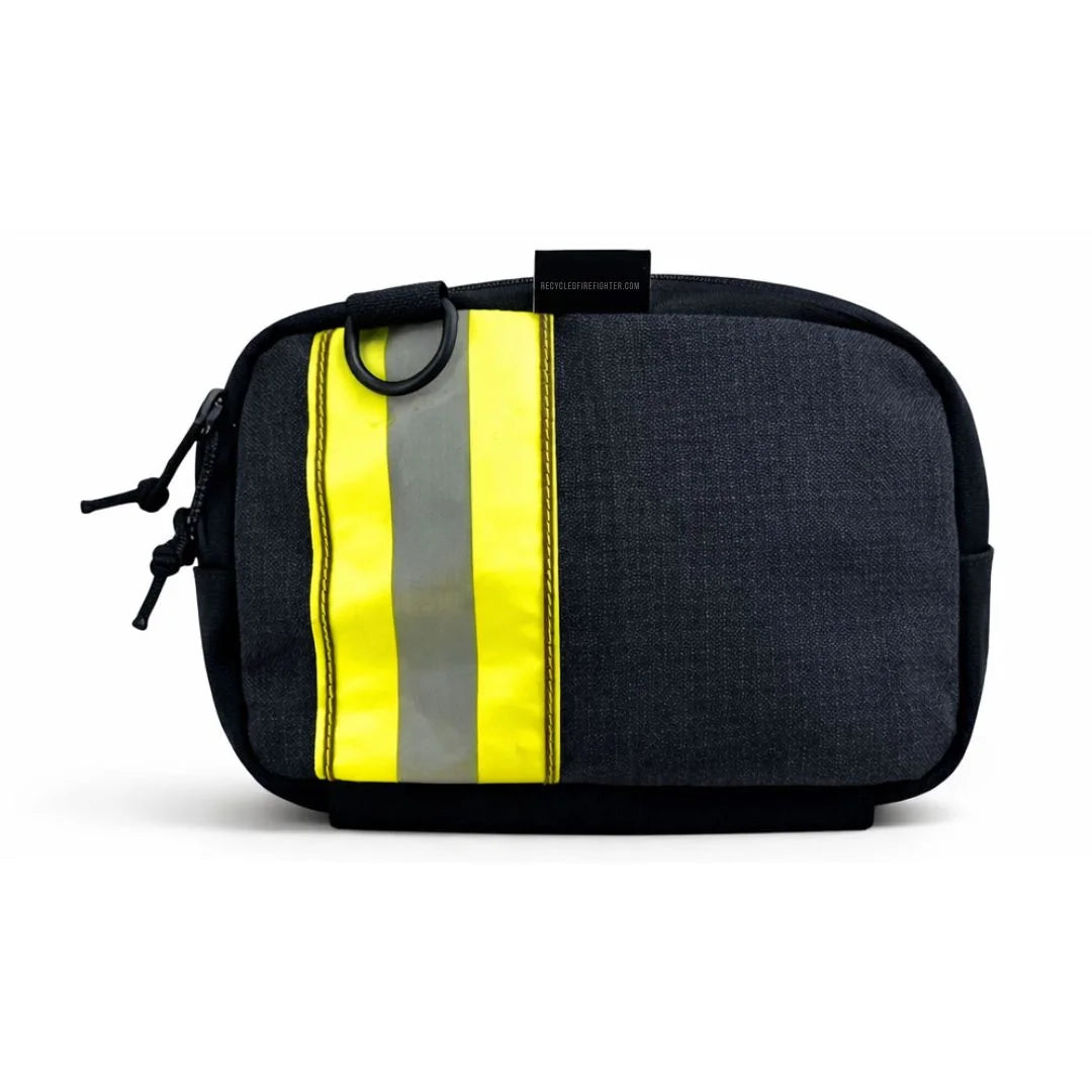 A black bunker gear fanny pack from Recycled Firefighter with a bold horizontal yellow and silver reflective stripe. The tactical-style bag includes a black adjustable waist strap and a brass side grommet for dog waste bags.