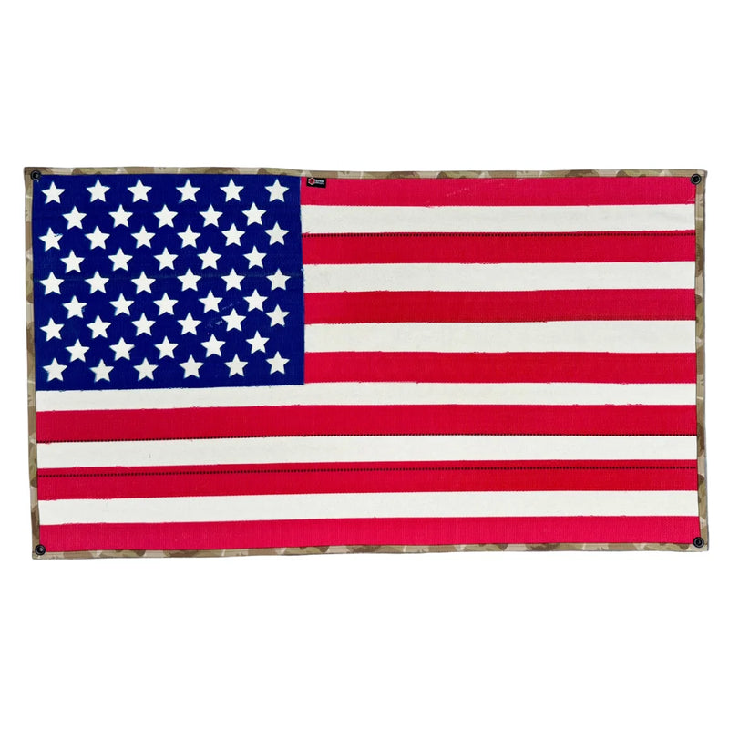 A large American flag by Recycled Firefighter handcrafted from decommissioned 5-inch fire hose with a Coyote Arid border and four brass mounting grommets.