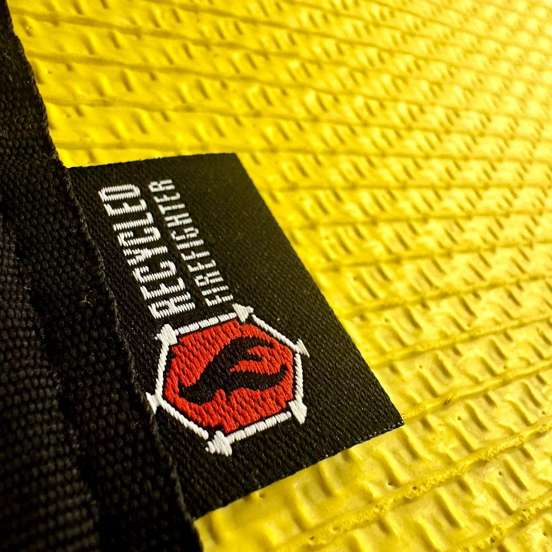 A heavy-duty Drop Zone Mat HD Attack Hose Edition made from repurposed yellow fire hose provides a durable, oil-resistant work surface for firearm maintenance and gear organization.