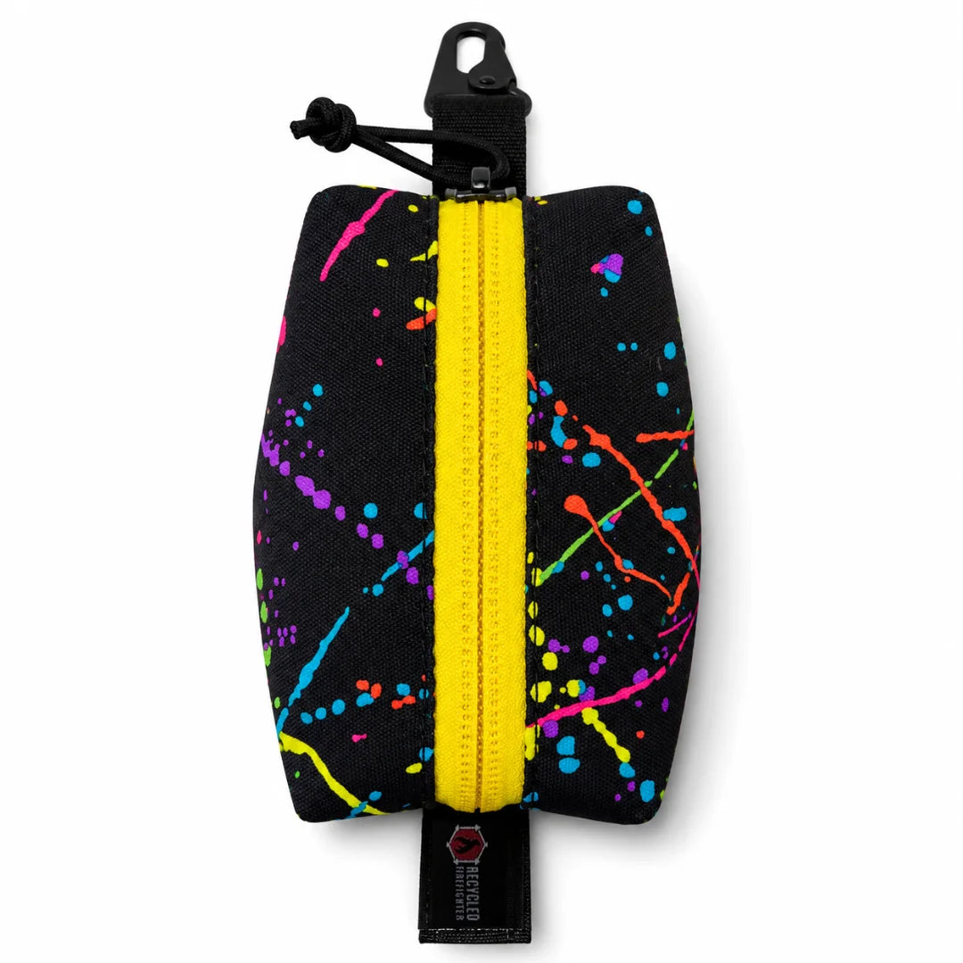 Recycled Firefighter's Hot Shot Commander Keychain Pouch in Splatter with Black Pull pairs an eye-catching splatter-print exterior with a stealthy black zipper pull for a distinctive EDC carry solution. Handcrafted in the USA, this clip pouch attaches securely to keys, belt loops, or pack webbing.