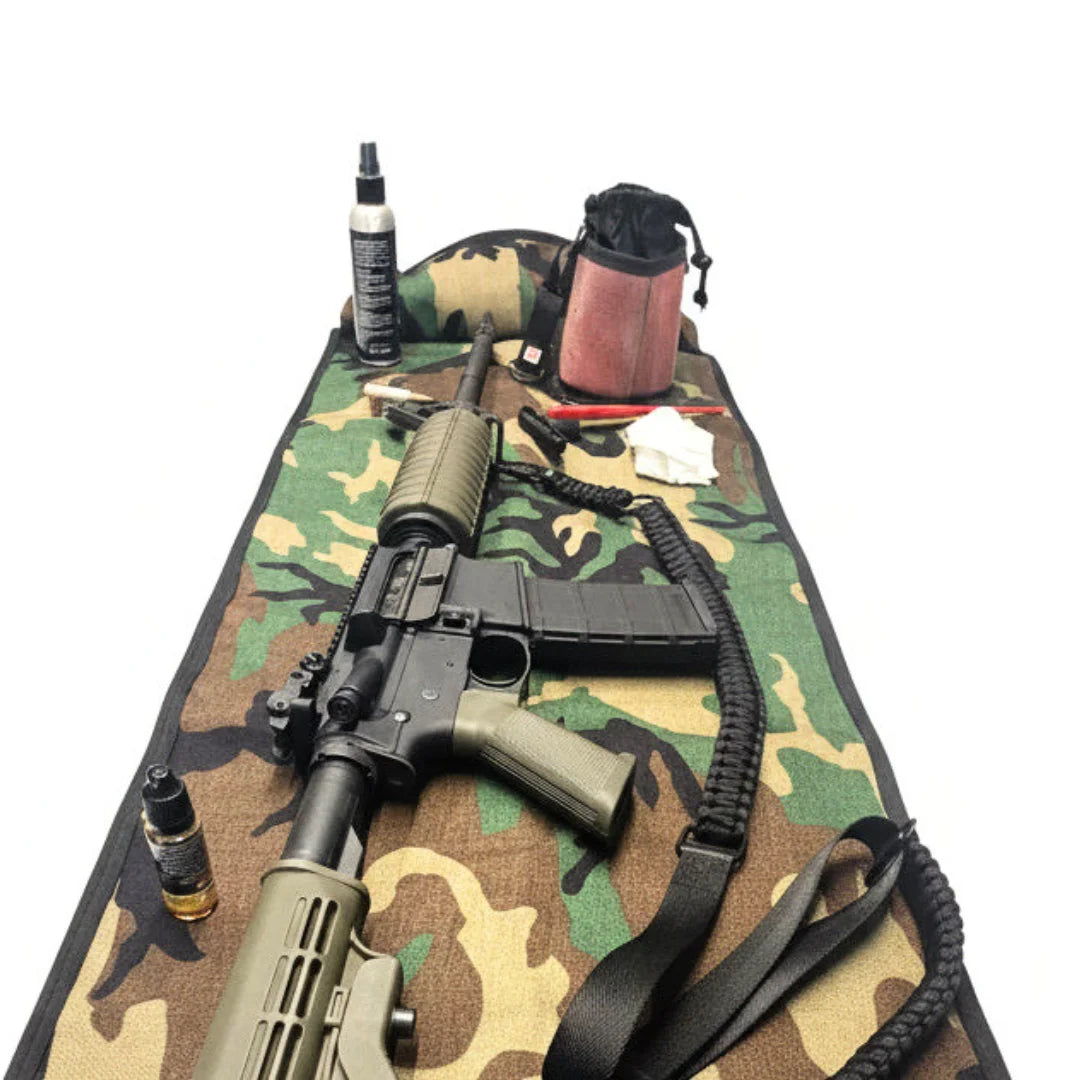 Recycled Firefighter Long Rifle Mat Firehose Edition in Vintage Green & Woodland laid out with a rifle and Ammo Gear Bag, left side view. A 40" x 16" USA-made range mat handcrafted from authentic fire hose with a built-in YKK zippered pouch.