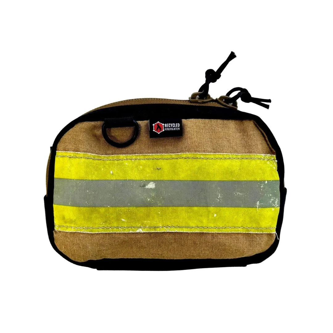 A brown bunker gear fanny pack by Recycled Firefighter featuring a wide, horizontal yellow and silver reflective safety stripe across the front. The pack is made from authentic repurposed firefighter turnout gear with black zippers and a side grommet.