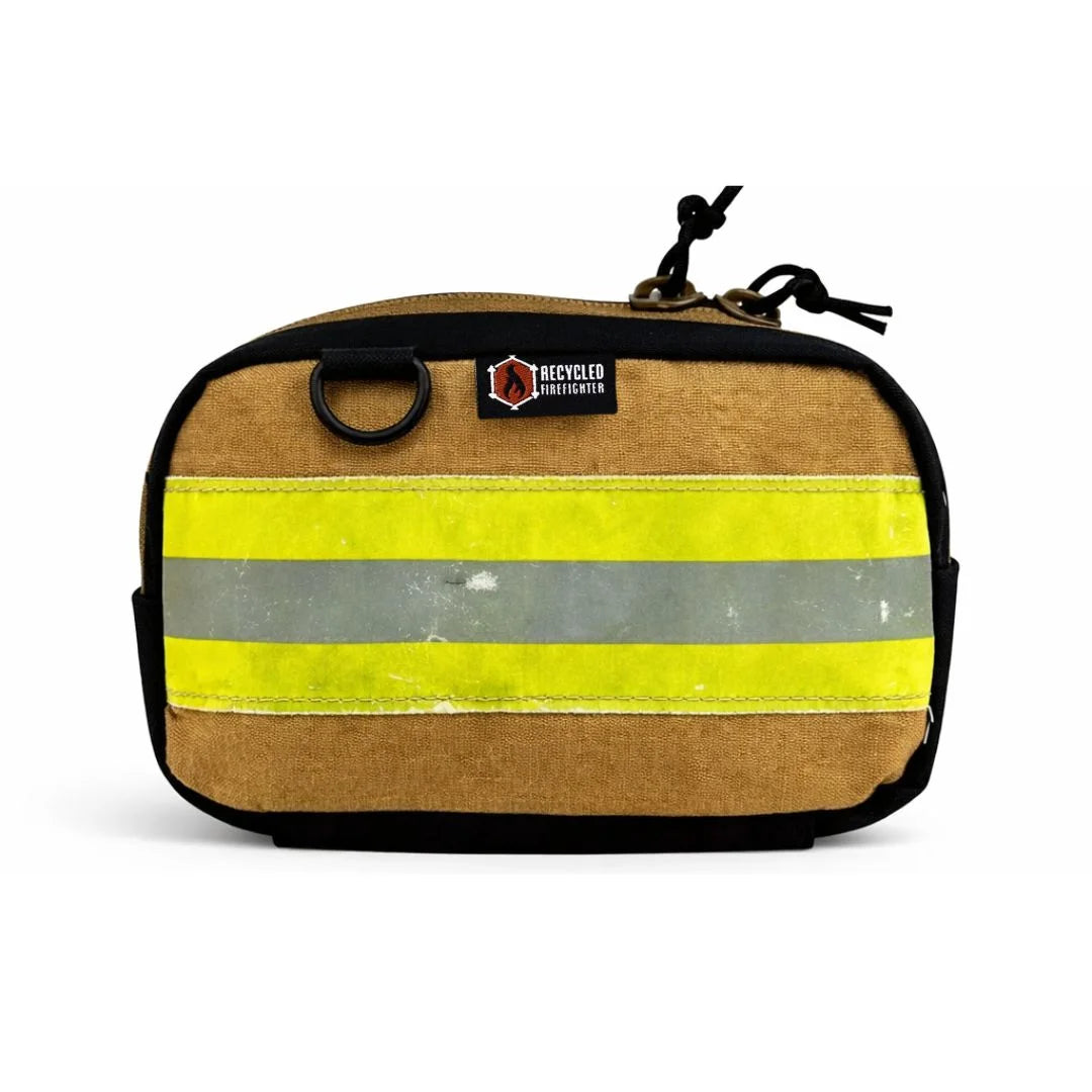 A brown bunker gear fanny pack by Recycled Firefighter featuring a wide, horizontal yellow and silver reflective safety stripe across the front. The pack is made from authentic repurposed firefighter turnout gear with black zippers and a side grommet.