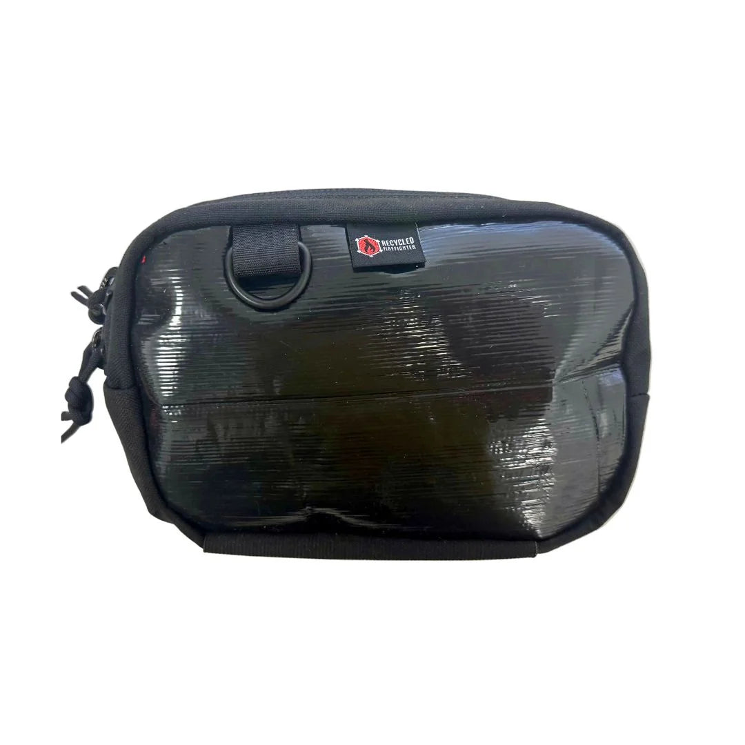 A sleek Black Rubber firehose fanny pack from Recycled Firefighter. Made from the internal lining of a decommissioned firehose, this variant has a smooth, semi-matte black finish that is highly water-resistant, featuring all-black hardware.