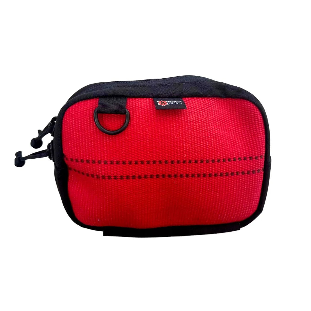 A vibrant red firehose fanny pack by Recycled Firefighter. This variant uses clean, bright decommissioned firehose material for a bold look, accented by a black YKK zipper and a tactical elastic gear loop on the bottom.