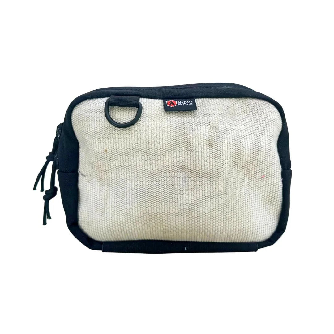 Recycled Firefighter fanny pack in Vintage White firehose. The off-white material has a rugged, industrial texture with subtle gray markings from its former life. It includes a 55-inch black adjustable waist strap and a side-mounted brass grommet.